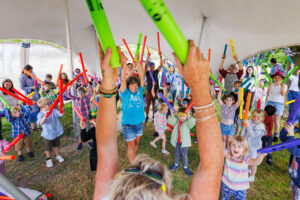 Lots of children in a gazevo, holding up boom whackers