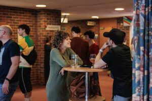 Two adults stood at a table with drinks in the bar area of Turner Sims