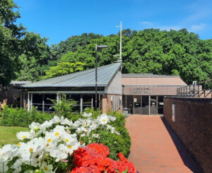 Red brick pathway leading to a building with an angular roof and reflective lettering saying Turner Sims.