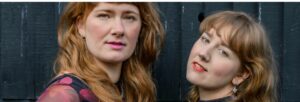 Two women with long hair gazing at the camera