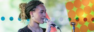 A young woman smiling and singing into a microphone