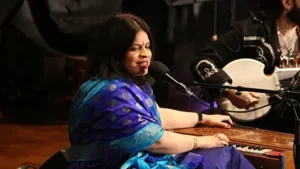 A woman sings into a mic while sat at a keyboard