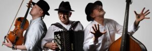 Three men in white shirts and black hats holding a fiddle, accordion and double bass