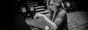 Young woman with long wavy hair playing a grand piano