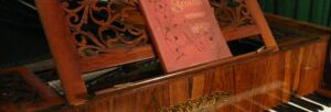 The lid and part of the keyboard of an antique piano with a book on the stand with the title 'Songs Without Words'