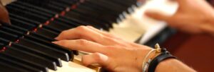 Hands playing a piano keyboard