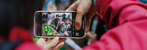 Hands holding a mobile phone, the screen of which shows two children with their faces painted